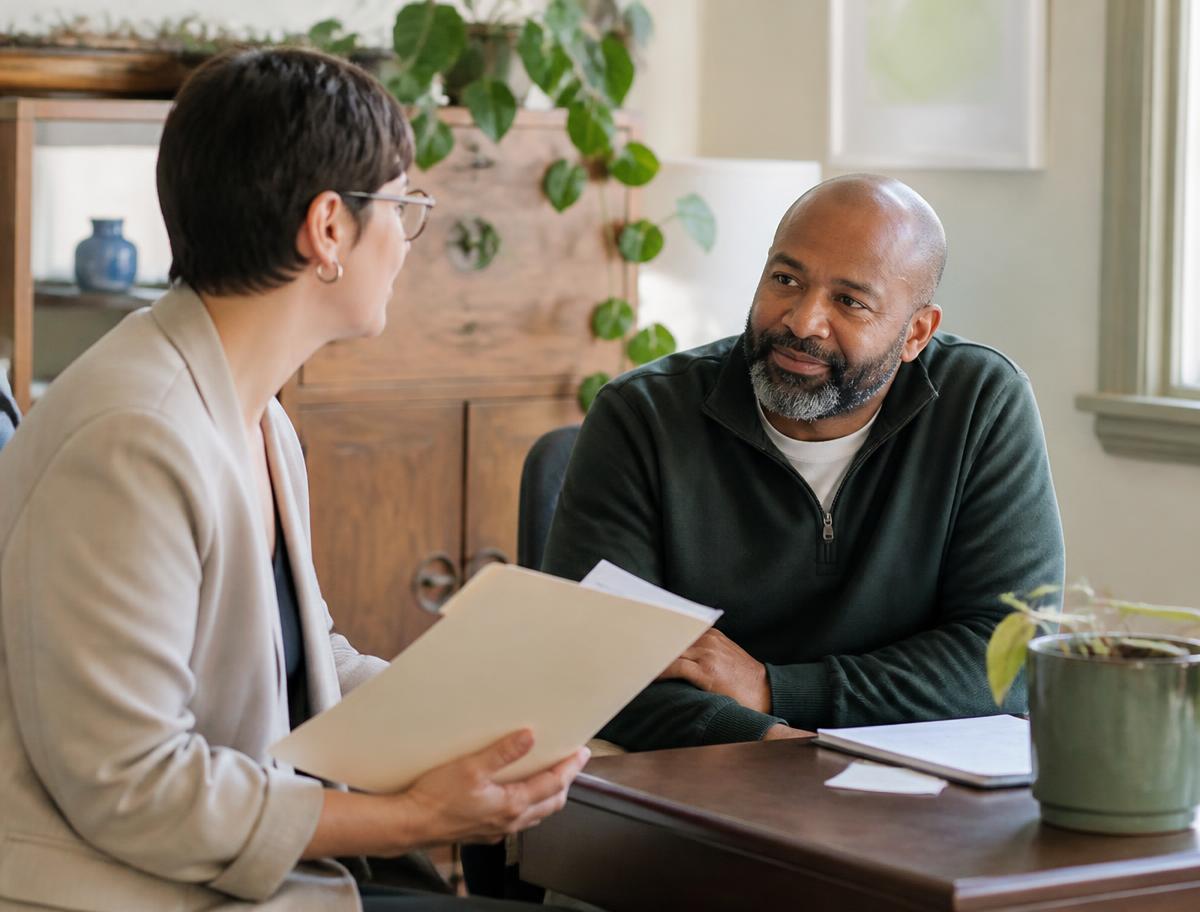 Two professionals talking across a desk in a warm community office